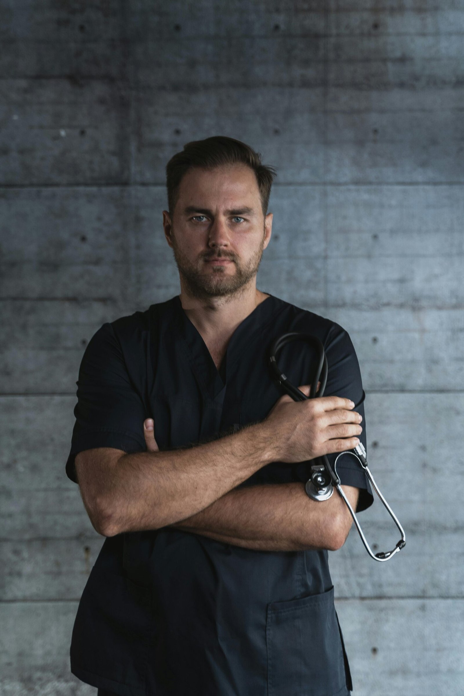 Portrait of a confident doctor standing with a stethoscope against a plain background, symbolizing medical professionalism.